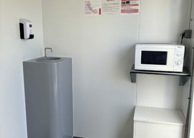 Intérieur de la roulotte de chantier Equiloc : lavabo autonome à pédale, distributeur de savon et micro-ondes